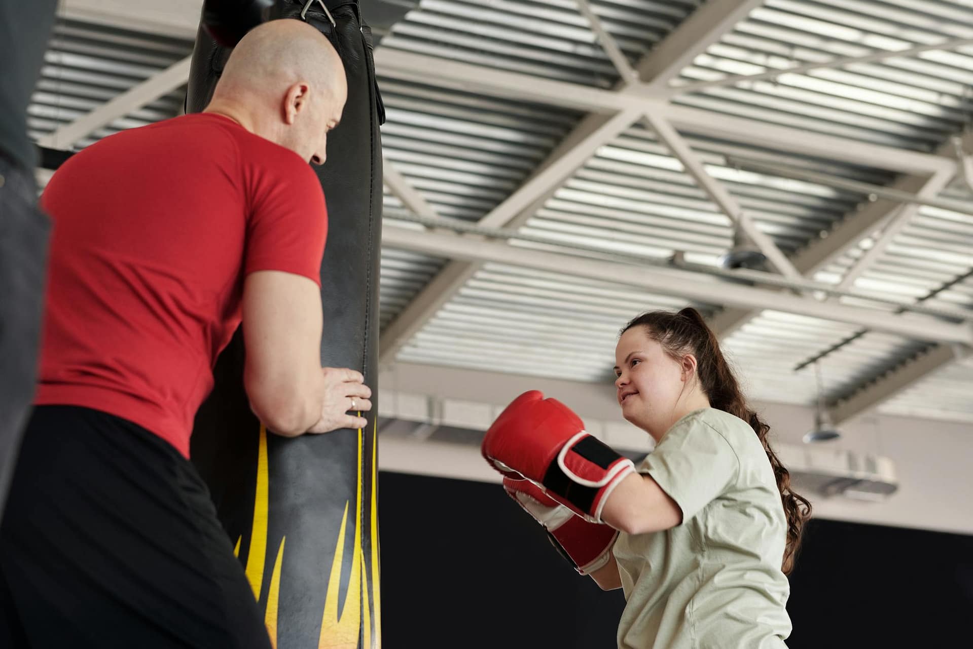 A woman with Down syndrome trains with a boxing coach, demonstrating empowerment and fitness.